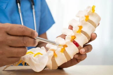 A pain management physician illustrates spinal stenosis on a model spine in North Dallas